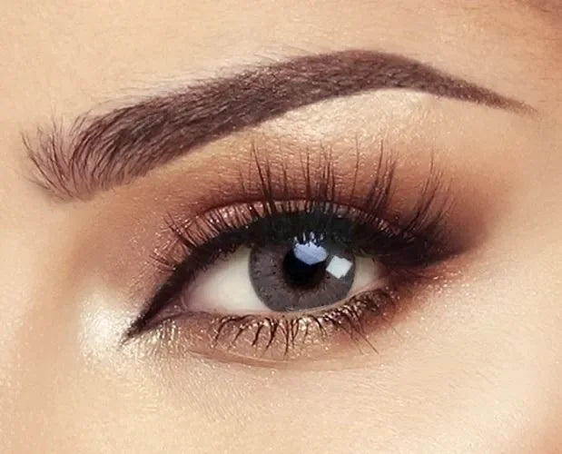 Close-up of Bella Elite Amber Gray Lenses on a white background, showcasing their natural gray hue with amber flecks.