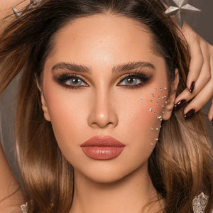 Bella DYE Stardust Monthly Lenses in a clear case, showcasing a starry, iridescent blue-green eye effect.